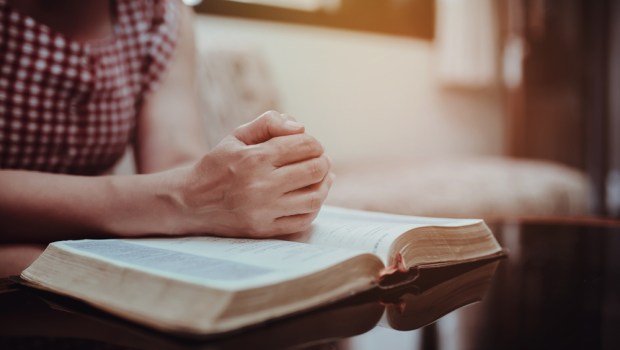 kobieta czyta Biblię siedząc na kanapie