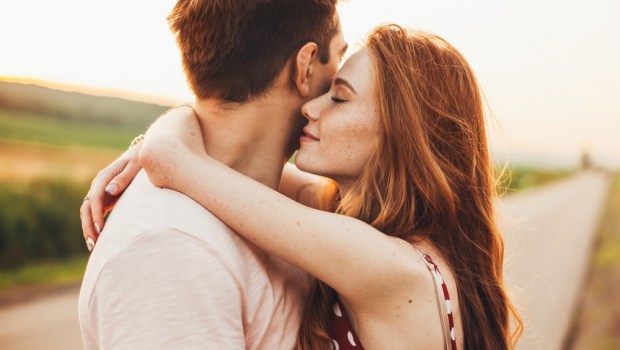 Close-up portrait of a caucasian young loving couple embracing while standing on a roadside. Couple embracing road travel. Sunset scene. | date,romance,couple,caucasian,happy,enjoying,spouse,smile,road,kissing,embracing,season,female,smiling,wife,dates,enjoyment,ginger,person,looking,autumn,adult,love,handsome,woman,weekend,cute,two,fall,romantic,street,walking,man,relationship,together,lovely,break,nature,valentine,portrait,lifestyle,afternoon,standing,sunlight,outdoors,authentic,hug,family,posing,walk