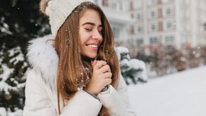 Radosna kobieta cieszy się śniegiem w wielkim mieście.
