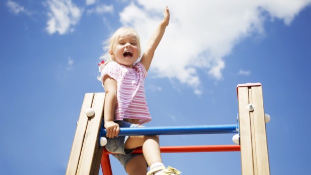 Sweet little girl outdoors with their hands raised
