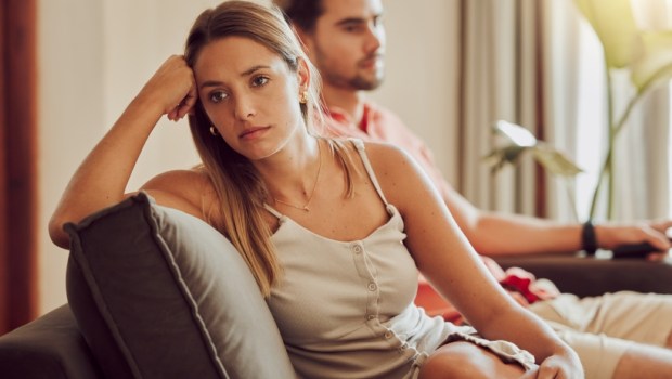 Unhappy, sad and annoyed couple after a fight and are angry at each other while sitting on a couch at home