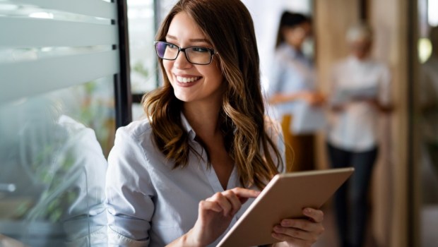 Young happy business woman working with tablet in corporate office