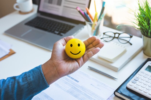Mão segurando bolinha de emoji feliz