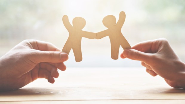 couple holding in hands wooden toy men as symbol of love and friendship