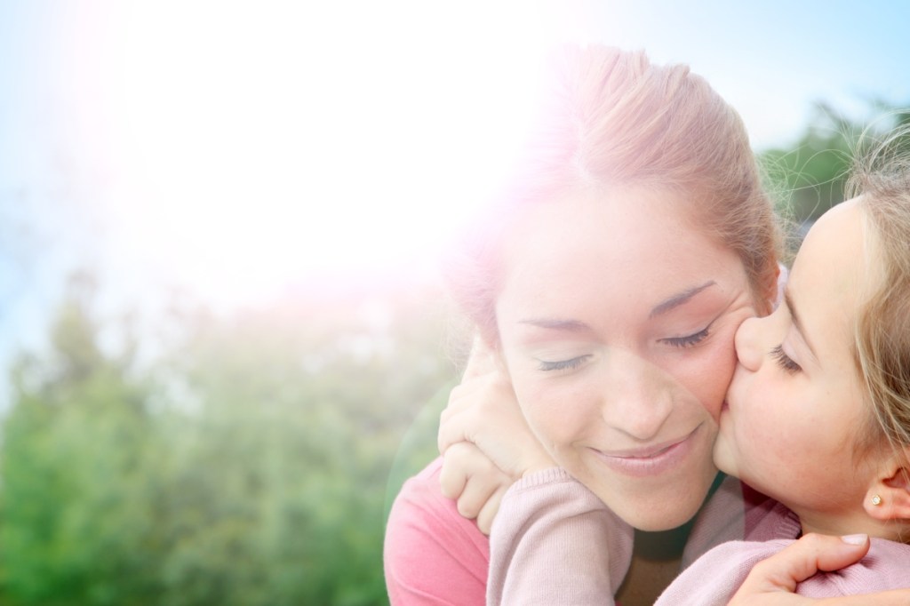 Portrait of little girl giving kiss to her mom