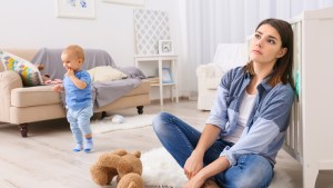 Depressed young woman with cute baby at home