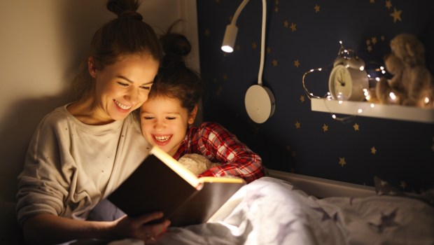woman and girl smiling and reading fairytale