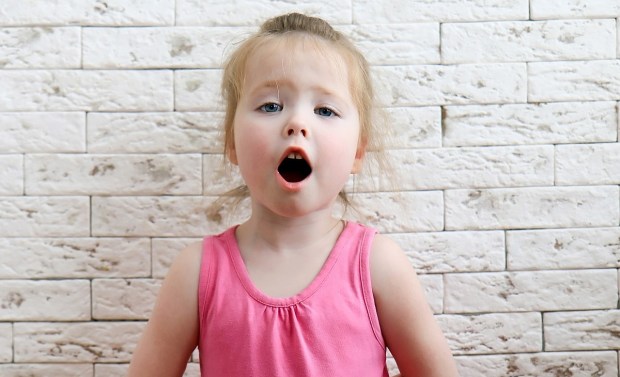 Little girl singing against brick wall