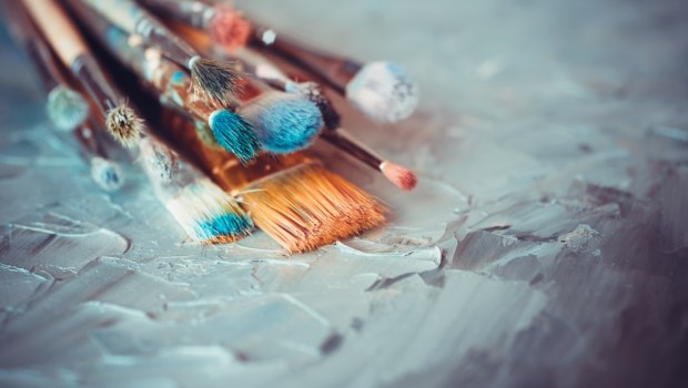 Paintbrushes on artist canvas covered with oil paints